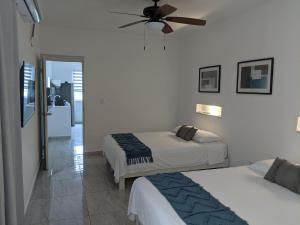 坎昆Hermoso departamento en Cancún YaxBahia 3的一间卧室配有两张床和吊扇