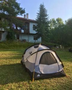 达达伊Balabanağa Çiftliği Camping的坐在房子前面的草上的一个帐篷