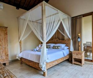 乌布Villa Ulun Mertha - 1BR Private Villa的卧室配有带白色床单和枕头的天蓬床。