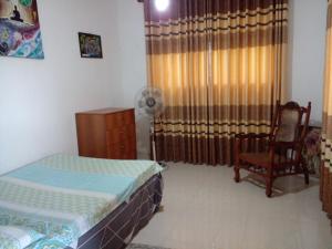 卡卢特勒Muthu Villa Sri Lanka的一间卧室设有两张床、一把椅子和一个窗户。
