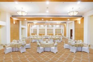 古尔冈古尔冈柠檬树高级酒店的一个带桌子和白色椅子的大型宴会厅
