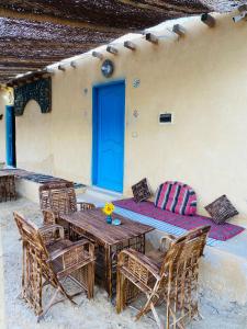 ‘Izbat an Nāmūsخزفستا Khazfista的一个带桌椅的庭院和一扇蓝色的门