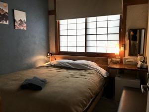 田边市DJANGO Hostel & Lounge的一间卧室配有一张床、一张书桌和一个窗户。