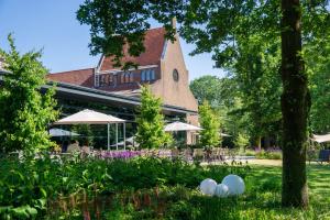 苏斯特贝赫Hotel Kontakt der Kontinenten的公园内带桌子和遮阳伞的建筑