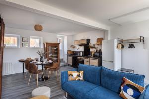 康卡勒La Maison de Louise - Superbe maison avec patio的一间带蓝色沙发的客厅和一间厨房
