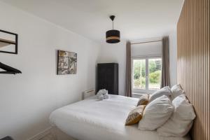 康卡勒La Maison de Louise - Superbe maison avec patio的卧室配有带枕头的白色床和窗户。