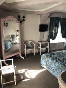 利勒阿当LE CABOUILLET的一间卧室配有一张床、镜子和椅子