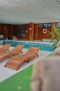 贝希特斯加登贝洛别墅酒店的游泳池前带木制躺椅的游泳池