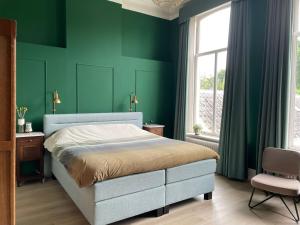 OudenboschBed & Breakfast By Genck的一间卧室设有绿色的墙壁、一张床和椅子
