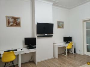 布鲁塞尔The Brussels-Laken Appartement的客房设有两张桌子和一台墙上的电视