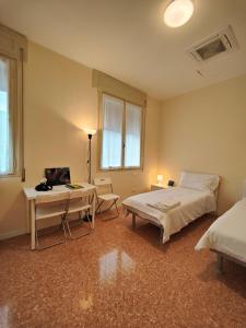维托里奥·威尼托Casa dello Studente的一间卧室配有两张床、一张桌子和一张书桌