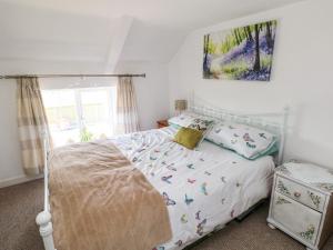 巴里港Daisys Cottage的一间卧室配有一张带白色床罩的床,上面有鸟儿
