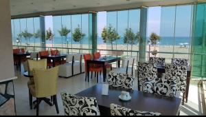 萨卡里亚Kocaali Sun Otel的一间带桌椅的餐厅,享有海滩美景