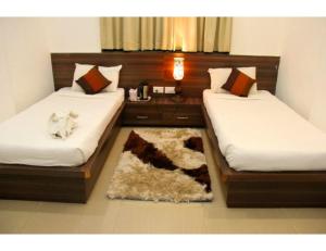 那格浦尔Hotel Flora Inn, Nagpur的一间设有两张床的房间和一张地毯