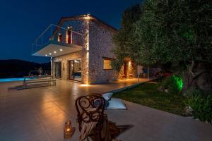 凯里翁Arca Villa - Enchanting Sunset!的石头房子,晚上在庭院里设有长凳