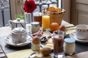 比亚里茨Hôtel & Espace Bien-être La Maison du Lierre的一张早餐桌,包括鸡蛋和一篮橘子