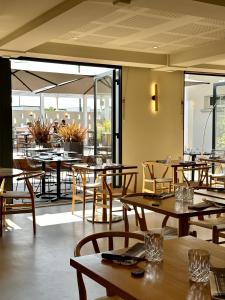 弗兰奎维尔-圣皮尔Logis Hôtel & Restaurant Le Vert Bocage的餐厅设有木桌、椅子和窗户。