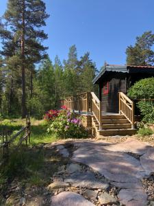 卡尔斯塔德Timber cottages with jacuzzi and sauna near lake Vänern的树林中的小屋,设有通往门廊的走道