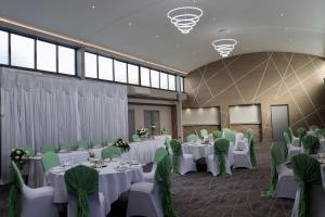 布里真德Best Western Premier Heronston Hotel & Spa的宴会厅配有白色桌子和绿色椅子