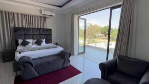 弗里尼欣Lifestyle Lodge Hotel的一间卧室配有一张床、一把椅子和一个大窗户