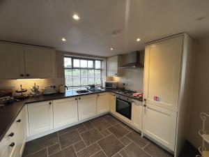约克Tanyard Cottage - Whixley, York, North Yorkshire的一间设有白色橱柜和窗户的大厨房