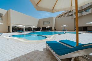 赫尔格达Aqua Mondo Abu Soma Resort的一个带蓝色躺椅和遮阳伞的游泳池