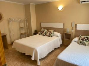 塔韦尔内斯德拉瓦利迪格纳Hotel Valldigna的一间卧室配有两张带白色床单的床