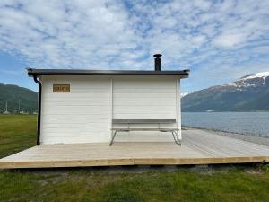 SamuelsbergLøkvollstranda camping As的水体旁边的码头上设有长凳的建筑物