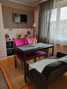 马里博尔Apartmaji Sofia的客厅配有桌子和粉红色椅子