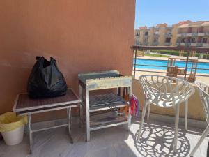 艾因苏赫纳Sun Mirror Chalet El Sokhna的阳台配有两把椅子、一张桌子和一个袋子