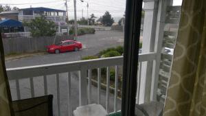雅茅斯VILLAGE GREEN MOTEL的一辆红色的汽车从阳台驶向街道