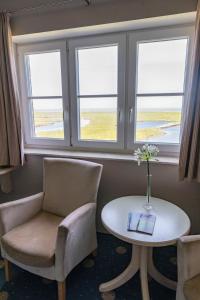 朗格内斯岛Anker's Hörn - Hotel & Restaurant auf der Hallig Langeness的客房设有桌椅和窗户。