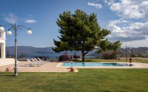 伊斯米亚Villa Fantasia Isthmia的一个带树、椅子和灯的游泳池