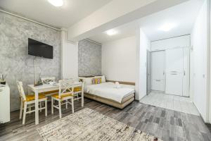 布拉索夫JAD - Comfortable Family Apartments - Coresi的一间卧室配有一张床铺和一张桌子,还有一间用餐室