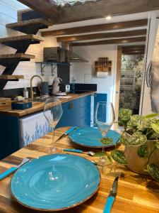 圣艾尼昂La Tiny Blue - maison insolite pour 2 - sans Tv的一张木桌,上面放着两个蓝色的盘子和酒杯