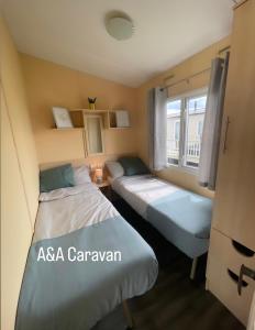滨海莱斯当A&A Caravan Holidays的小型客房 - 带2张床和窗户