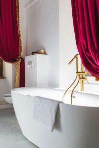锡比乌Sia Boutique Aparthotel的浴室设有白色浴缸和红色窗帘
