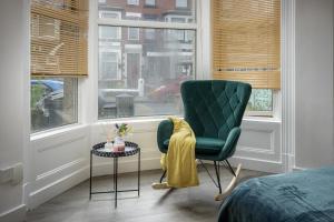 布莱克浦Seaside Suite 1 - Beautiful Long Stay Studio on Lord Street的一间卧室配有绿色椅子、桌子和窗户