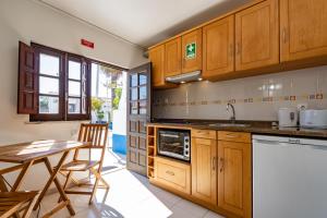 科武港Apartamentos Capitão by Umbral的厨房配有木制橱柜和桌椅