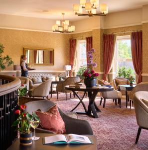 布莱辛顿图尔法利斯酒店及高尔夫度假村的酒店大堂设有桌椅和1名妇女站立