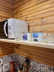 ArthonRomantique chalet avec sauna et jacuzzi extérieur的一个带杯子和玻璃杯的架子和微波炉