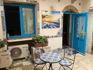 特拉帕尼Cortile Azzurro的庭院配有两把椅子和一张桌子,并设有两扇窗户。