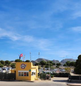 阿桂拉斯Bungalow Duemo Camperpark的上面有旗帜的黄色建筑