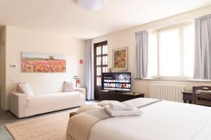 VertemateFLOWERS ROOM stanza privata tra Como e Milano的白色的卧室配有白色的床和沙发