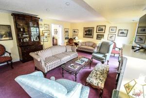 滨湖尼亚加拉Blairpen House Country Inn的坐在客厅里,配有沙发和椅子的女人
