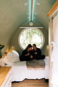 格伦科RiverBeds - Luxury Wee Lodges with Hot Tubs的两个女人坐在窗户房间里的床边