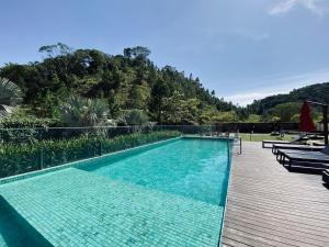 伊达贾伊The Green Hill com piscinas em Praia Brava的一座大型游泳池,其木制甲板毗邻山脉