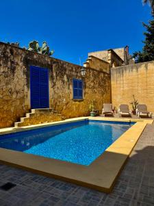 沙拉MJ Farmhouse B&B的一座带蓝色门的石头建筑前的游泳池