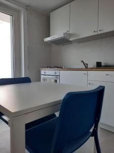 切萨雷奥港Kennedy Apartments- Porto Cesareo的厨房配有白色的桌子和蓝色的椅子