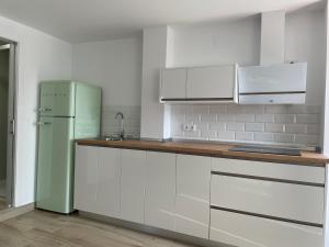 韦尔瓦Apartamento turístico Ático La Piterilla的厨房配有白色橱柜和绿色冰箱。